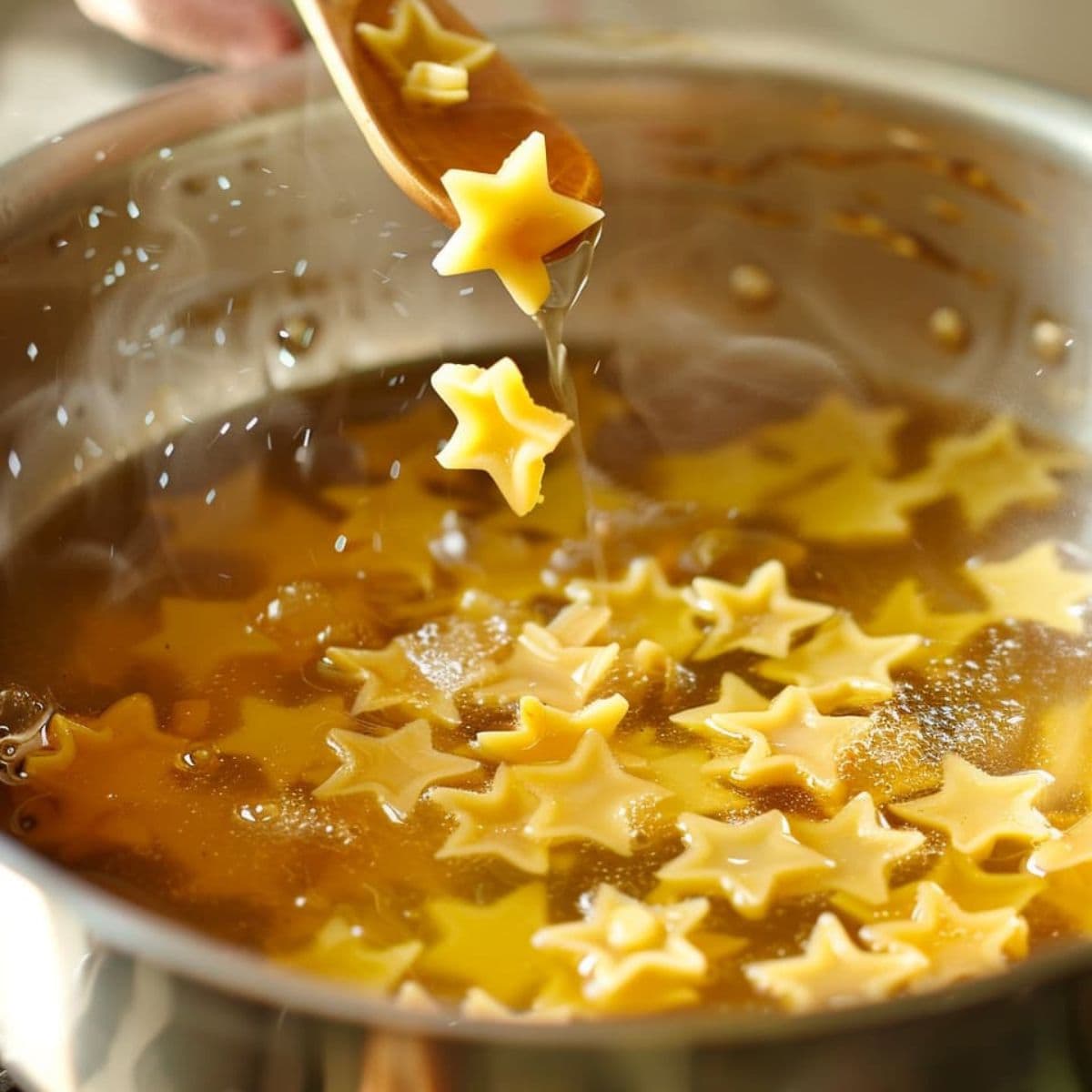 Tiny star-shaped pasta being poured and stirred into hot broth