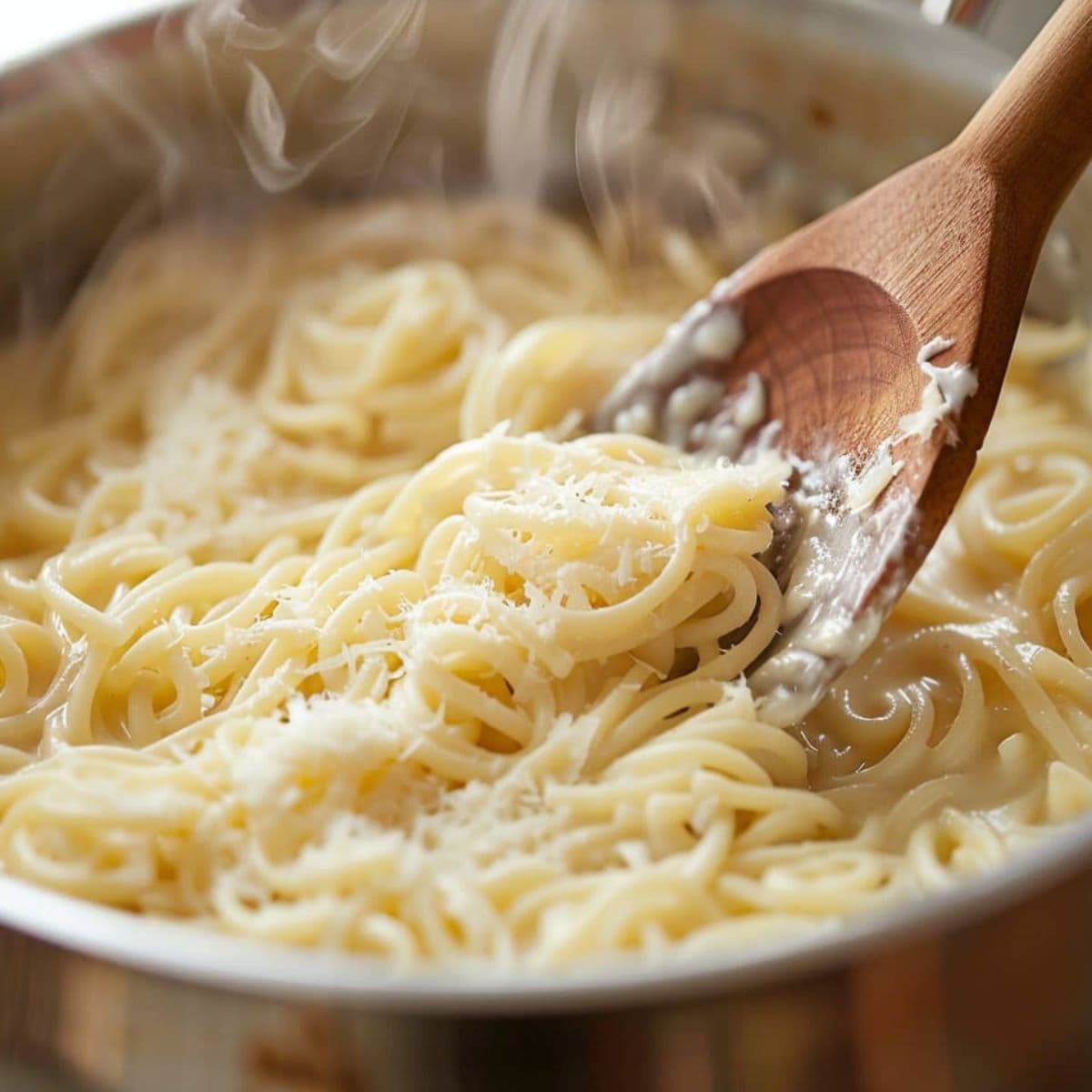 Butter and parmesan being stirred into cooked pastina off heat