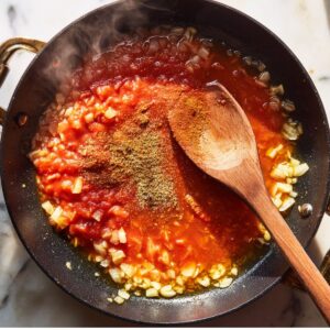 build the base for spanish rice recipe by cooking onions, garlic, tomato sauce, and spices