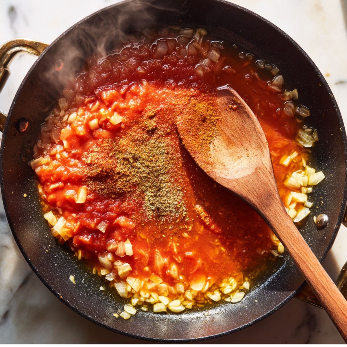build the base for spanish rice recipe by cooking onions, garlic, tomato sauce, and spices