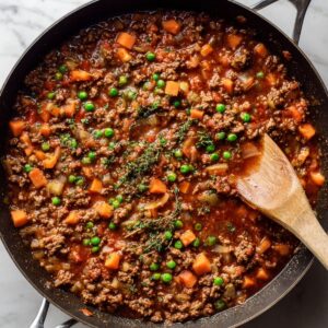 cook the meat base for cottage pie recipe with browned ground beef and vegetables simmering in a skillet