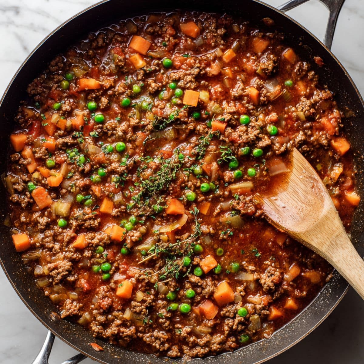 cook the meat base for cottage pie recipe with browned ground beef and vegetables simmering in a skillet