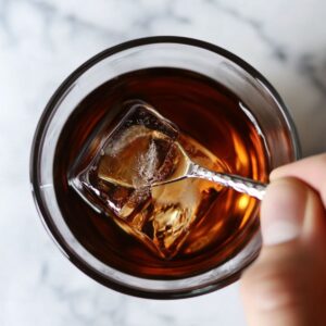 stirring black manhattan recipe over ice