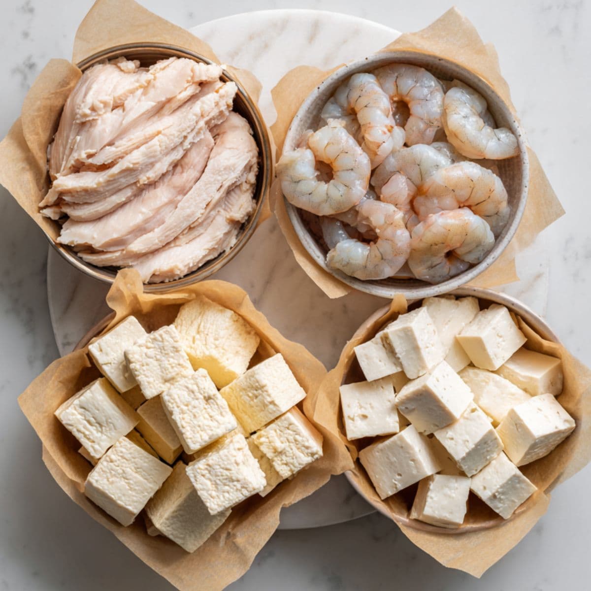 rasta pasta recipe proteins including chicken breast, shrimp, and tofu arranged on marble
