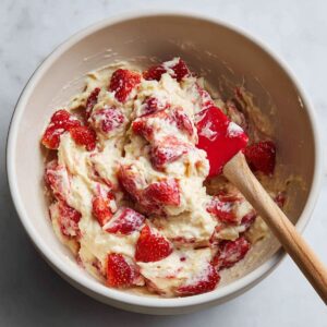 folding chopped strawberries into waffle batter for strawberry waffles recipe