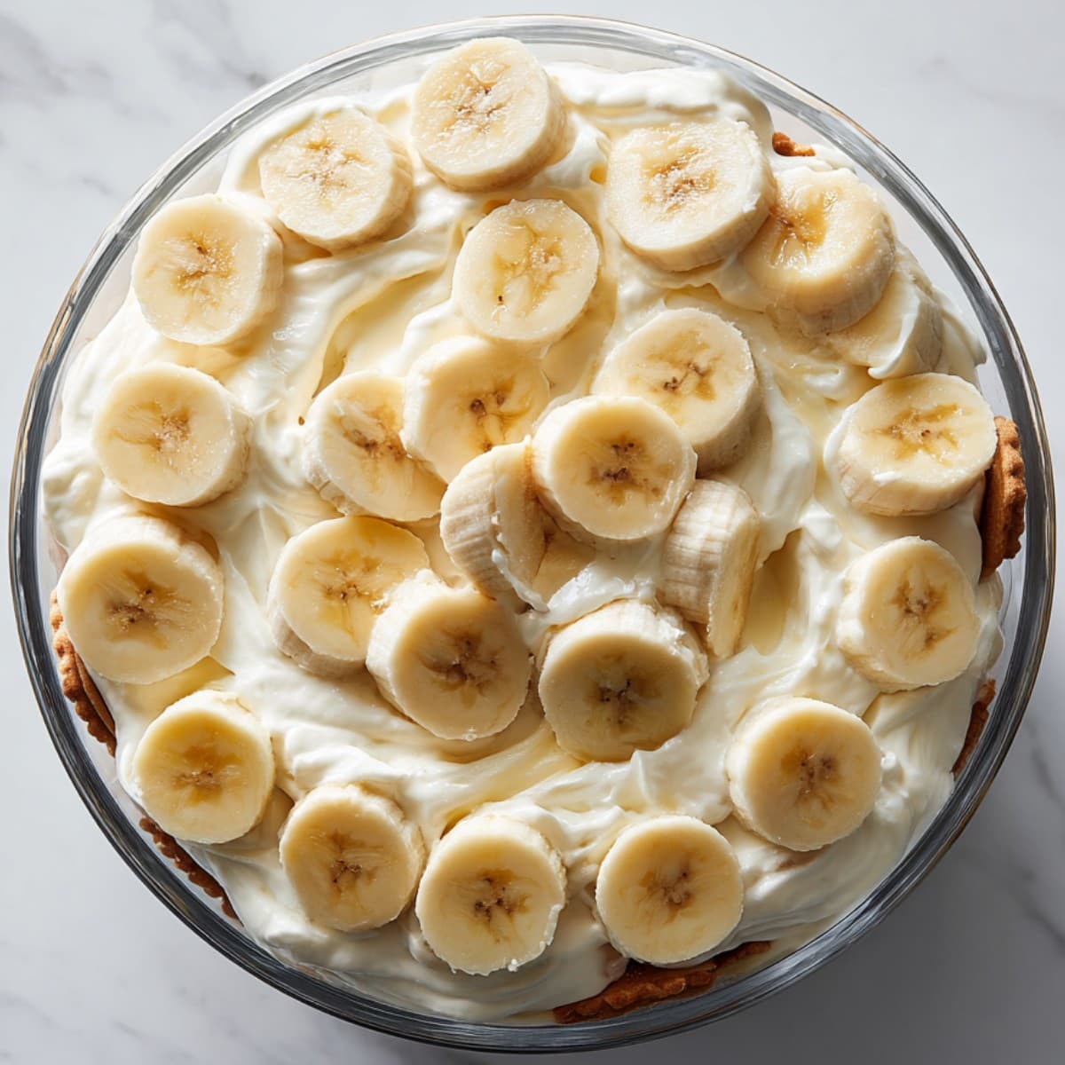 layering banana pudding recipe with wafers, pudding, and banana slices