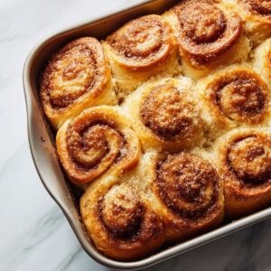 cinnamon rolls cut into equal pieces arranged in a greased baking dish, golden brown with visible swirls after rising and baking