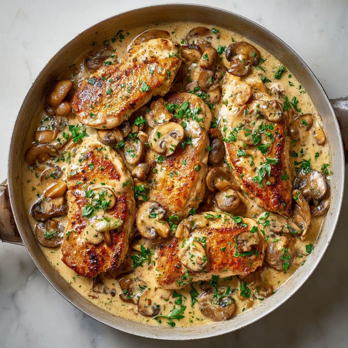 chicken simmering in creamy marsala sauce with mushrooms and parsley
