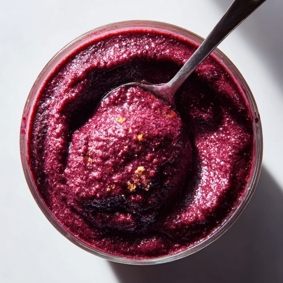 spoon standing upright in thick acai mixture inside a blender jar