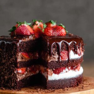 chocolate cake being layered with ganache and sliced strawberries before frosting