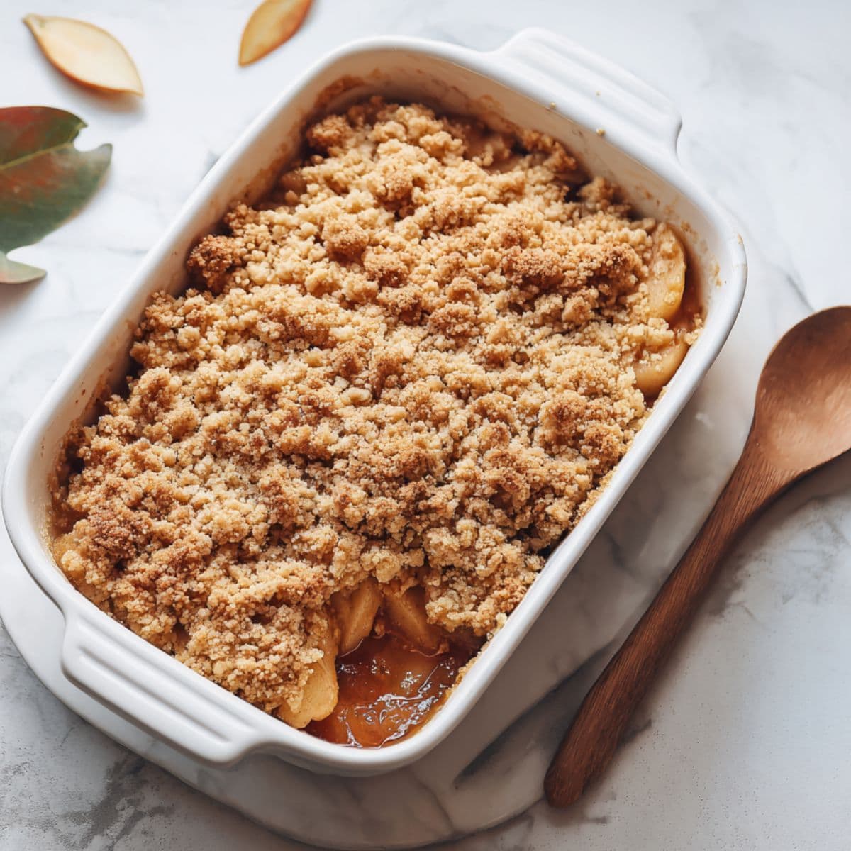 golden apple crumble with crispy oat topping and tender apples in white baking dish