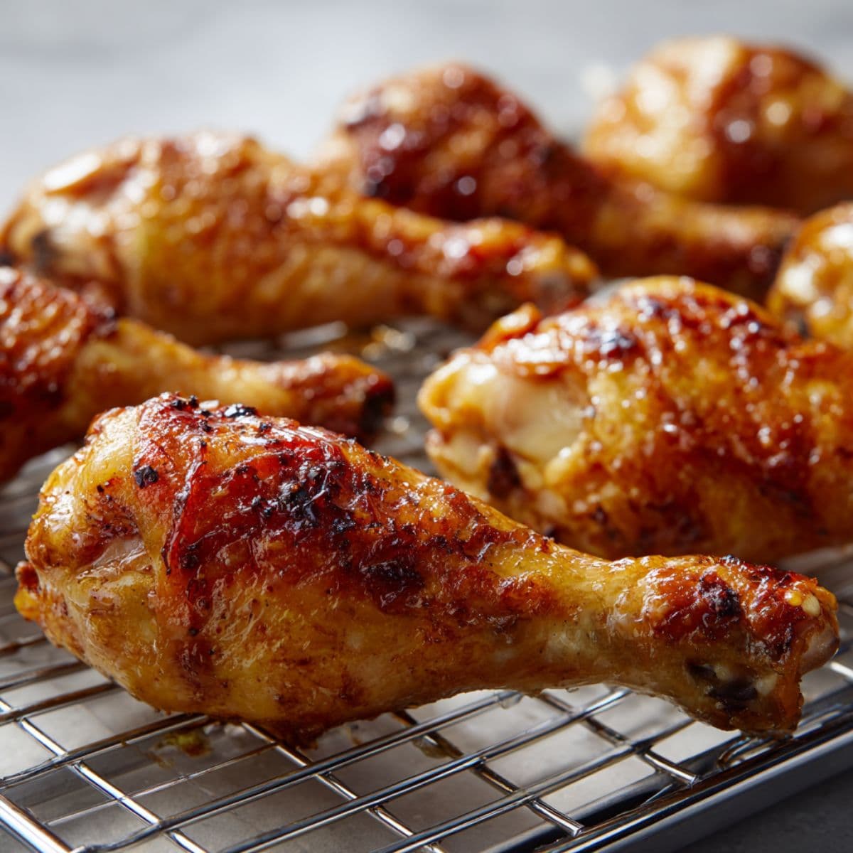 golden brown chicken drumsticks on wire rack over baking sheet just out of oven with crisp skin and meat thermometer showing 165 degrees