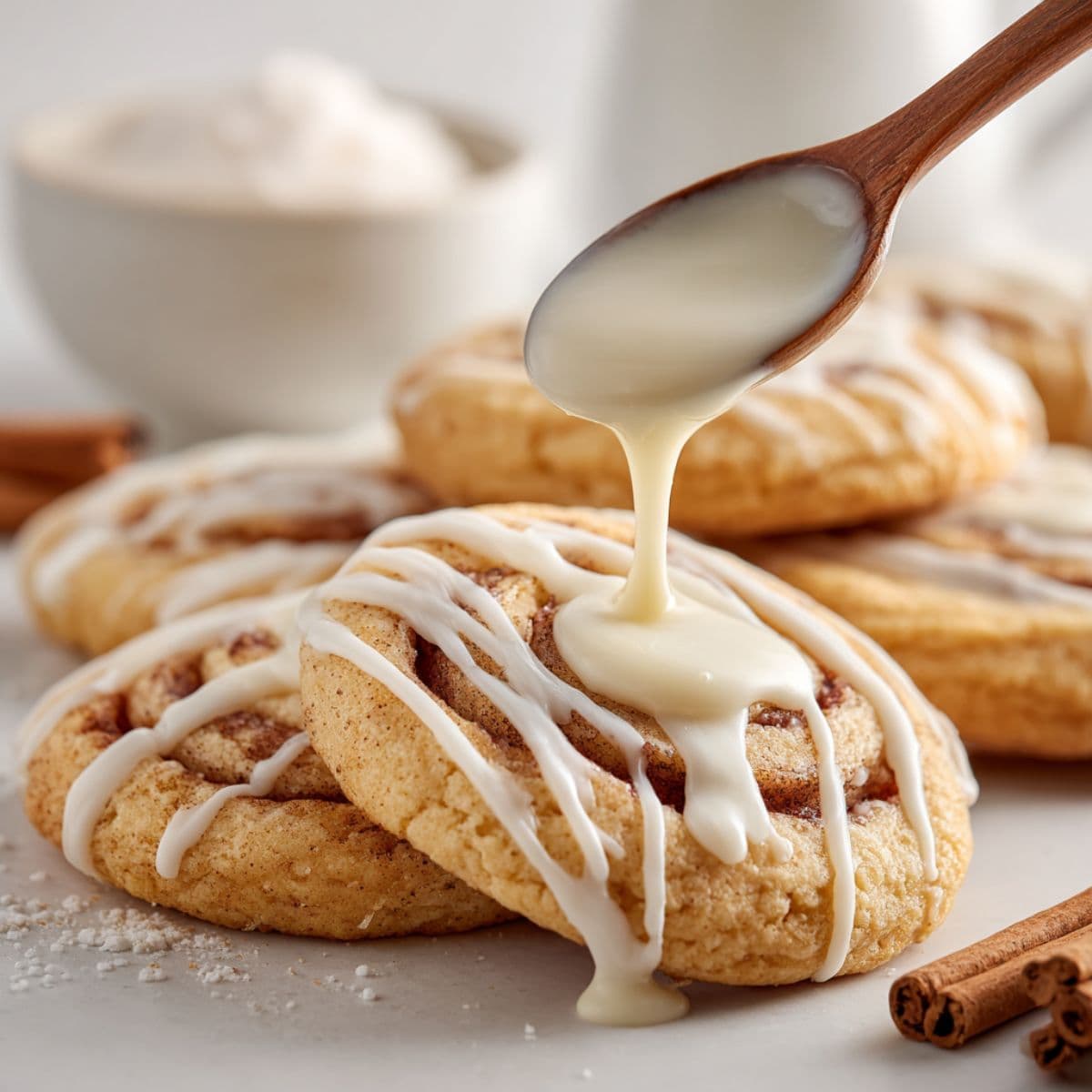 slightly warm cinnamon roll cookies with visible cinnamon swirls being drizzled with smooth cream cheese glaze