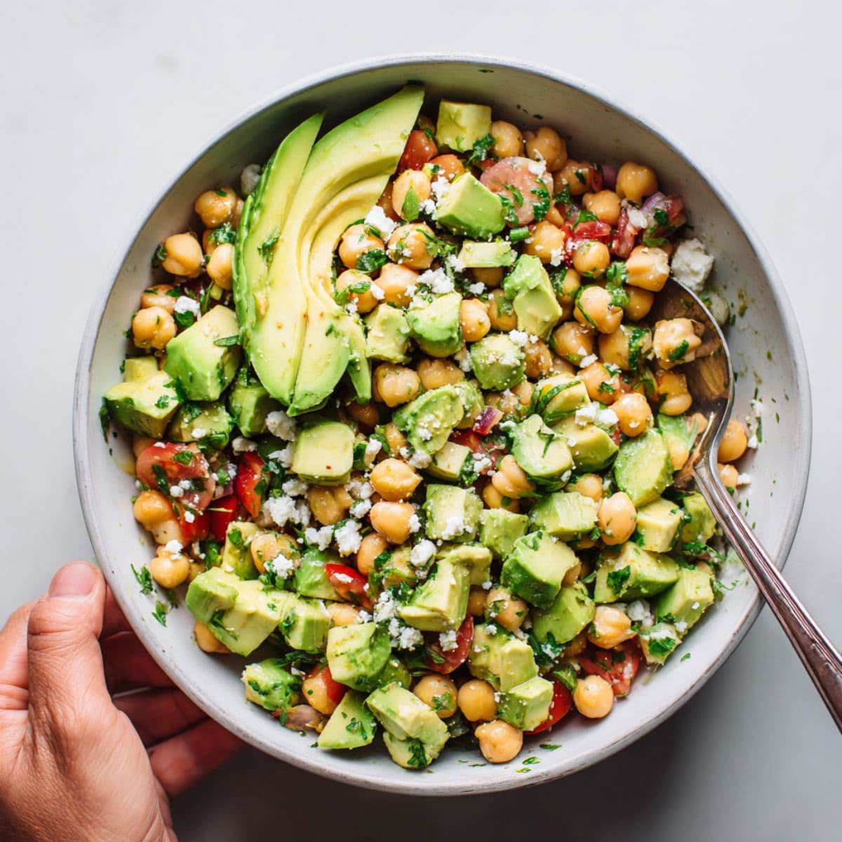 adding avocado to chickpea feta salad
