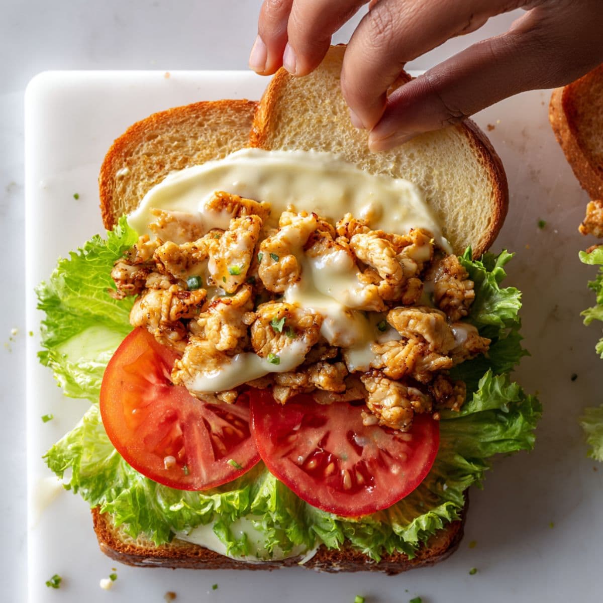 assembling garlic chicken sandwich with cheesy chicken