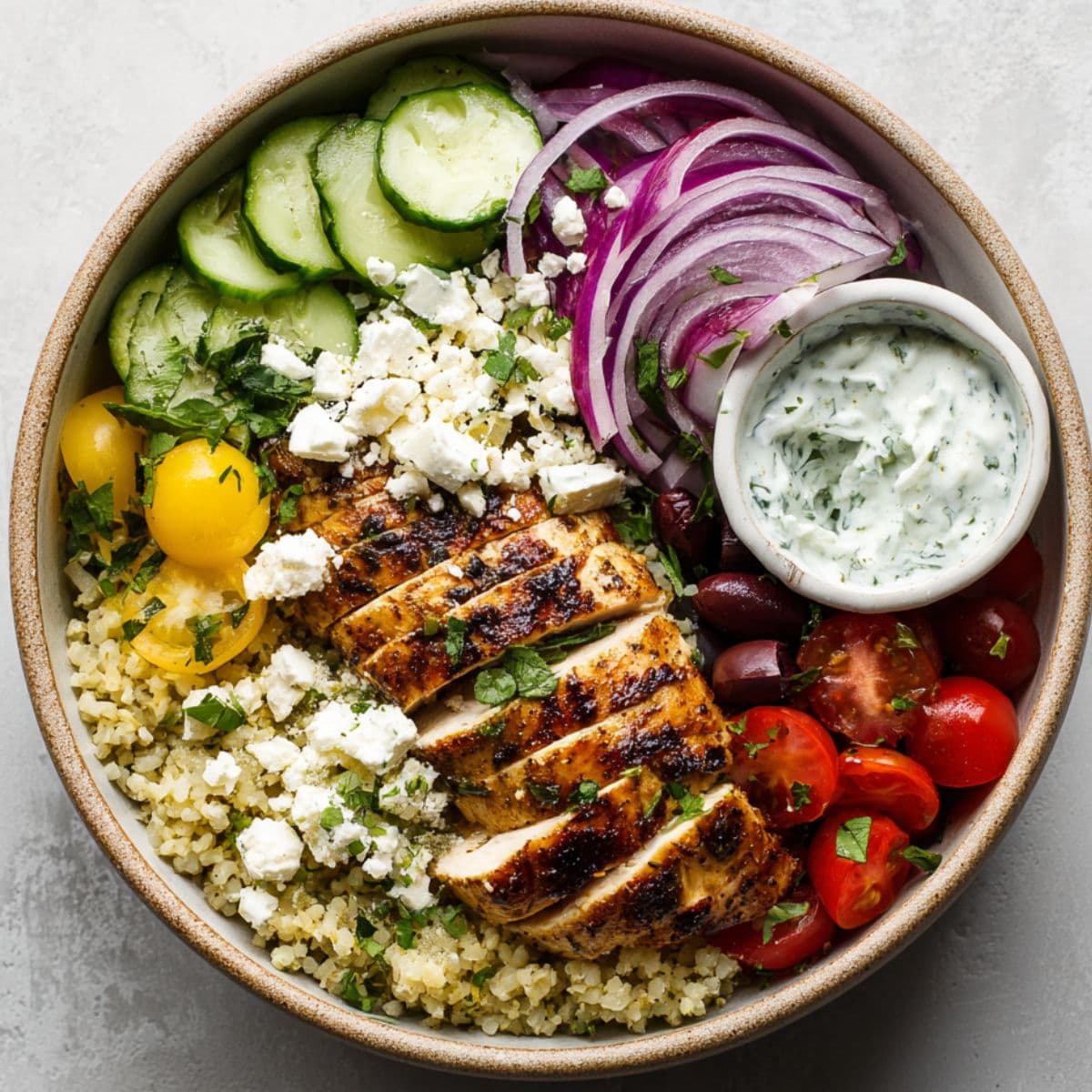 assembling greek chicken bowls with fresh toppings