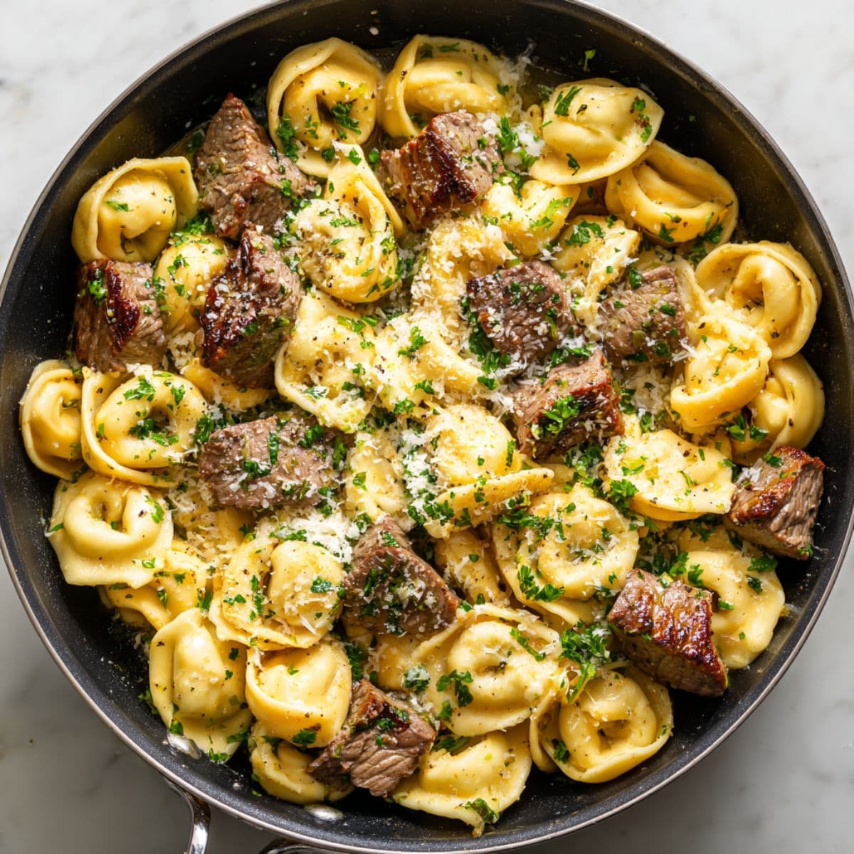 combining garlic steak tortellini in skillet