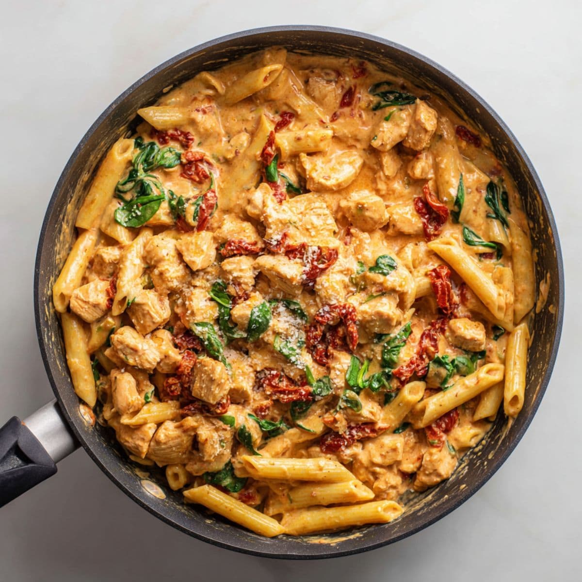 combining tomato chicken pasta in skillet