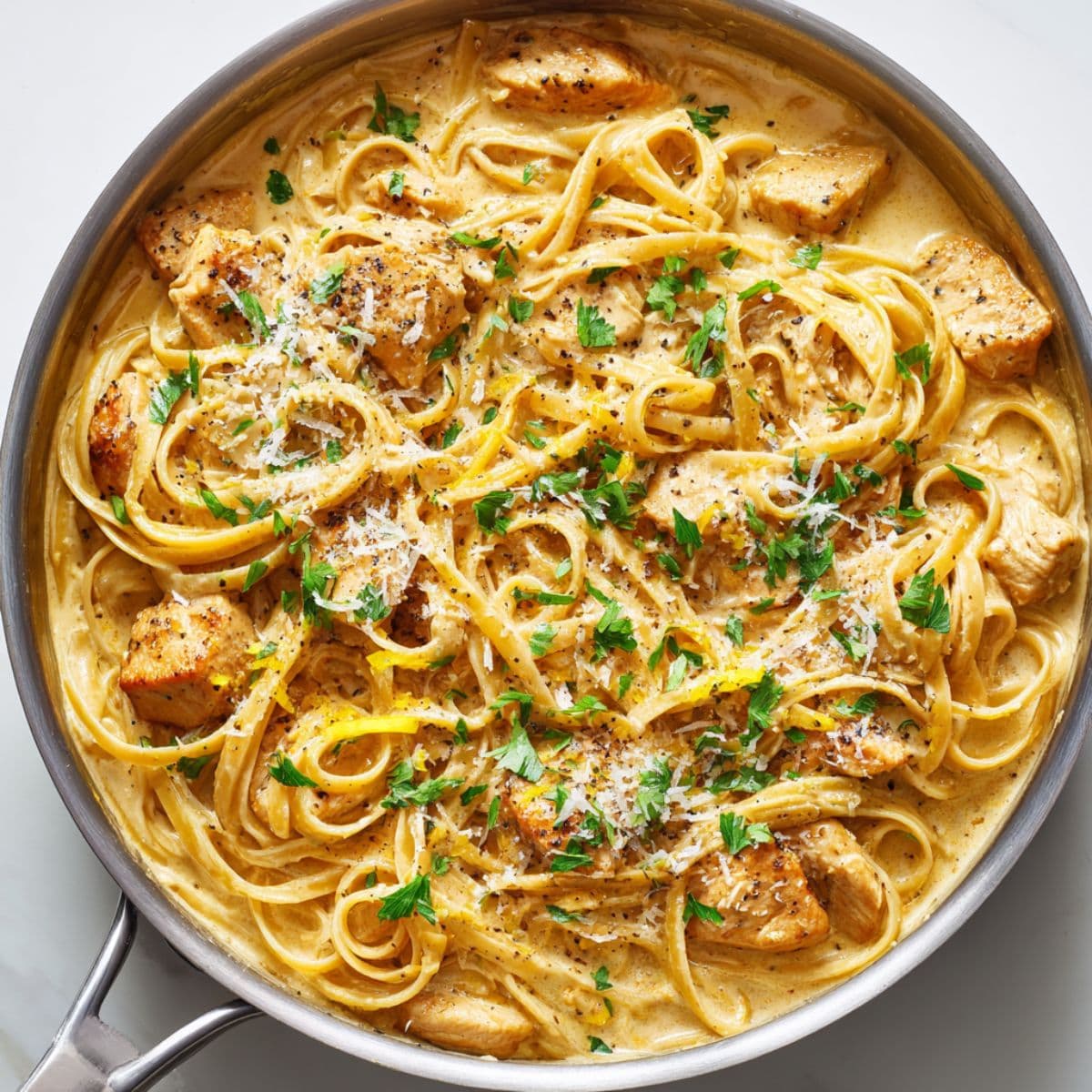 tossing cowboy butter chicken linguine in creamy parmesan sauce