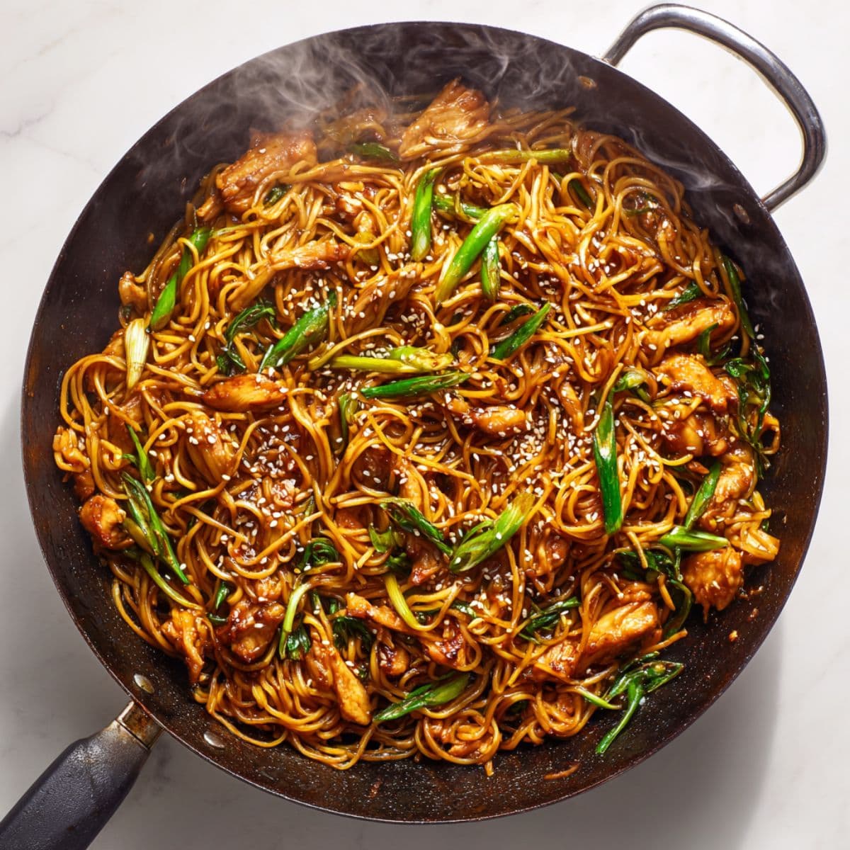 tossing sticky chicken noodles in glossy sauce